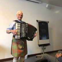 NHSCOT Trip to Scotland a picture of a accordion presentation by a scottish person