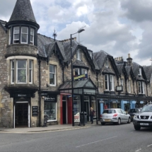 NHSCOT Trip to Scotland a picture of a scottish street complete with vehicles and stores