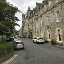 NHSCOT Trip to Scotland a view of a scottish street with cars and a hotel